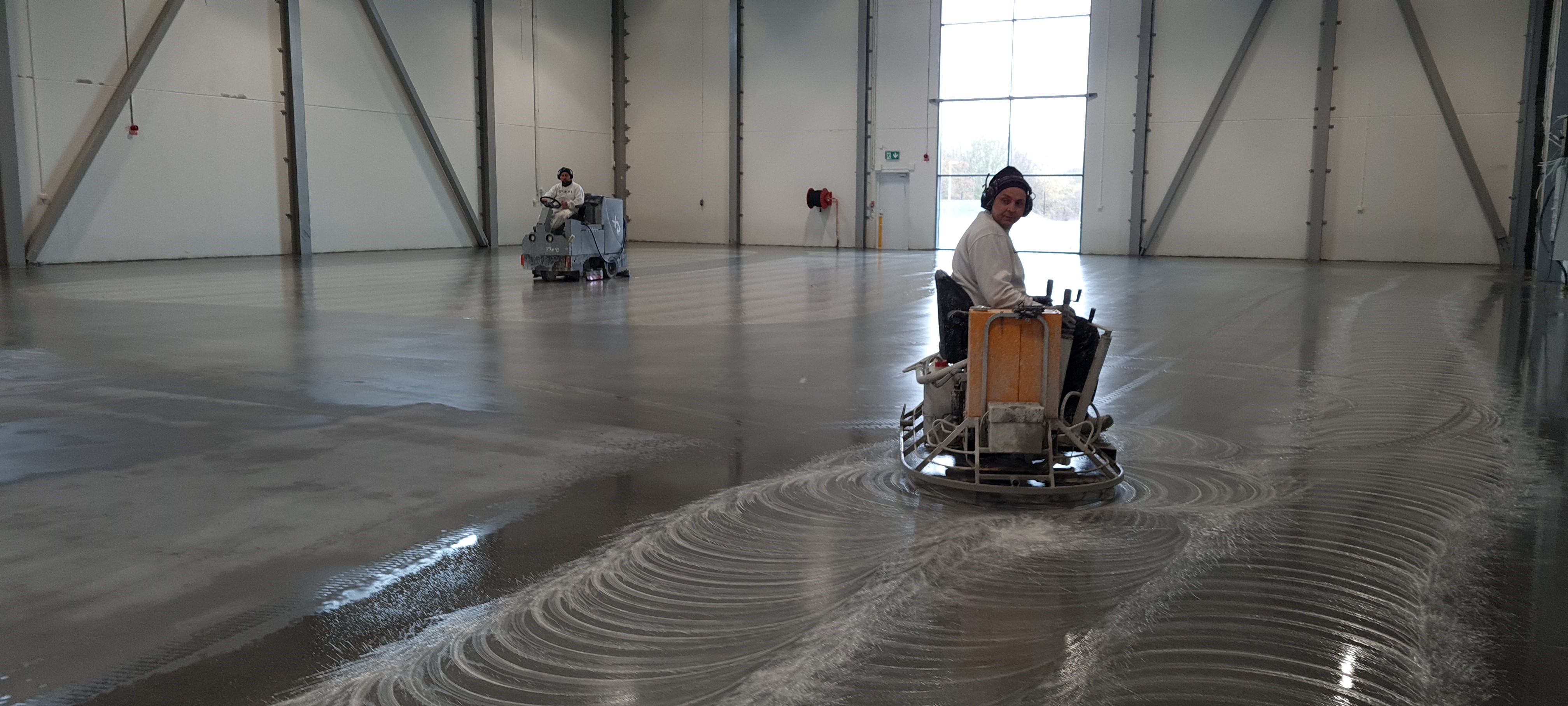 två män utför diamantslipning på betonggolv